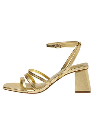 Gold strappy sandal with block heel, open toe, and ankle buckle strap, designed for women's formal or casual wear.