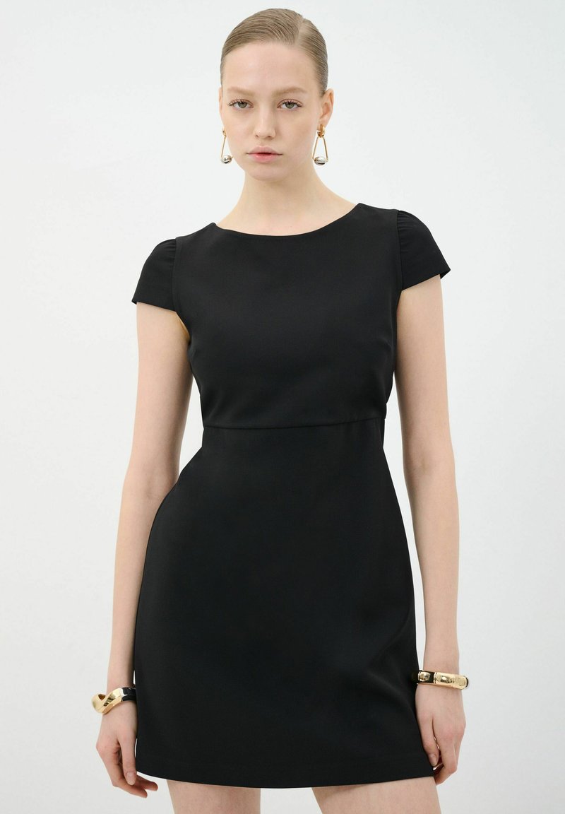 Vestido negro ajustado con mangas cortas, hecho de tela suave. Presenta un escote redondeado y una sutil línea de cintura imperio.