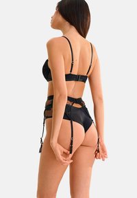 Zwart lingerie set met een kanten beha en hoogrispanty met verstelbare kousenbanden. Gladde stof met ingewikkelde kantdetails.