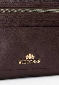 Brązowy, teksturowany skórzany portfel z złotym zamkiem błyskawicznym i wytłaczanym logo z akcentami lwa. Gładka powierzchnia z kontrastującymi detalami szwów.