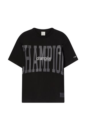 Camiseta negra de Champion con el gran texto gris "CHAMPION" y el logo más pequeño en blanco "champion NEW YORK" en el pecho, y el logo "C" de Champion en la manga.