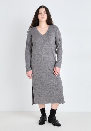 Gray, ribbed, long-sleeve dress with a V-neck, knee-high side slit, and a midi length, paired with black socks and loafers.