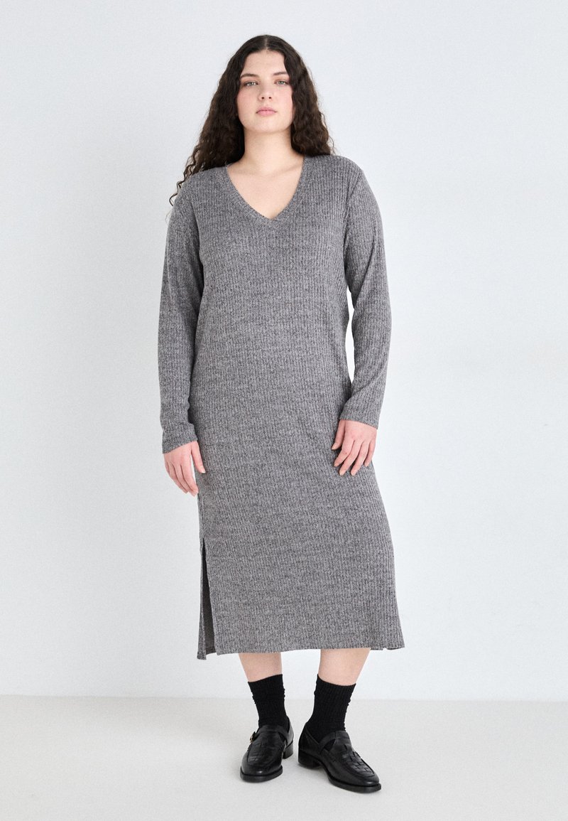 Rochie gri, cu nervuri, cu maneci lungi si decolteu in V, cu slit lateral pana la genunchi si lungime midi, asortata cu sosete negre si pantofi loafers.