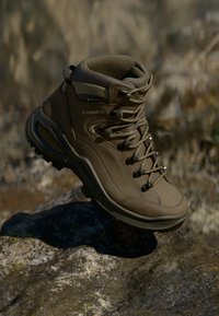 Brune tursko laget av syntetisk materiale, med midt-kutt design, teksturert overflate, snøresystem og gummiyttersåle for godt grep.