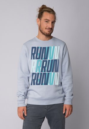 Lichtblauwe sweatshirt met een gedurfde, gelaagde "RUN" grafiek in verschillende tinten blauw. Heeft lange mouwen en ribgebreide manchetten.