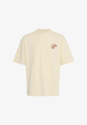 Kremowa bawełniana koszulka z luźnym krojem, okrągłym dekoltem, krótkimi rękawami i czerwonym nadrukiem na lewej części klatki piersiowej.