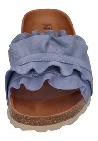 Ljusblå mockasandle med volangdetaljer, brun vadderad innersula och en strukturerad sula med en naturlig finish. Tillverkad i Spanien.