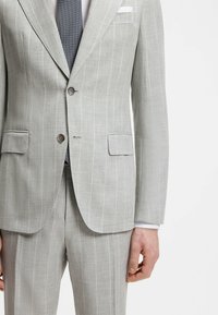 Hellgrauer Nadelstreifen-Anzug mit Jacke und Hose, Klappentaschen, Zwei-Knopf-Verschluss, weißem Hemdarm und dunkel gemustertem Krawatte.