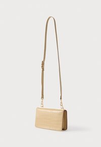 Bež torbica čez ramo iz teksturirane umetne usnje s kroko vzorcem, ki ima dolg nastavljiv trak in okraske v zlati barvi.