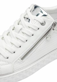 Sneaker bianca in pelle texturizzata, con accenti in tessuto e una zip argentata sul lato. Dotata di lacci bianchi piatti e una suola in gomma con motivo.