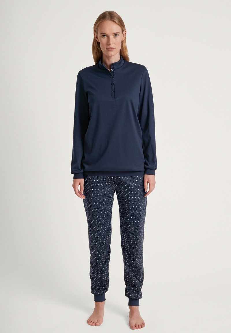 Marineblauw langemouwtop met een knoopsluiting en bijpassende pyjamabroek met een witte stippenpatroon en elastische manchetten.