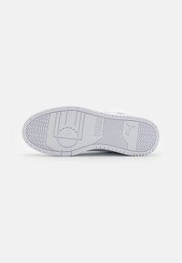 Biała podeszwa sneakerów z teksturowanymi wzorami, z logo i różnymi wzorami trakcji. Gumowy materiał zapewnia przyczepność i trwałość.
