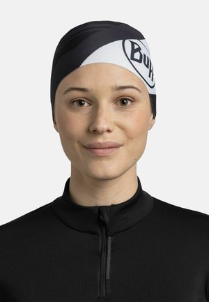Cinta para la cabeza Buff en blanco y negro con material suave y elástico; presenta un logotipo llamativo y un patrón diagonal. Lleva puesta una persona con una camiseta negra.
