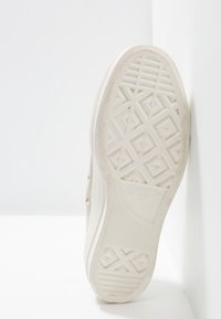 Suola di sneaker bianca Converse All Star con motivo a riquadri geometrici, fotografata su sfondo bianco.