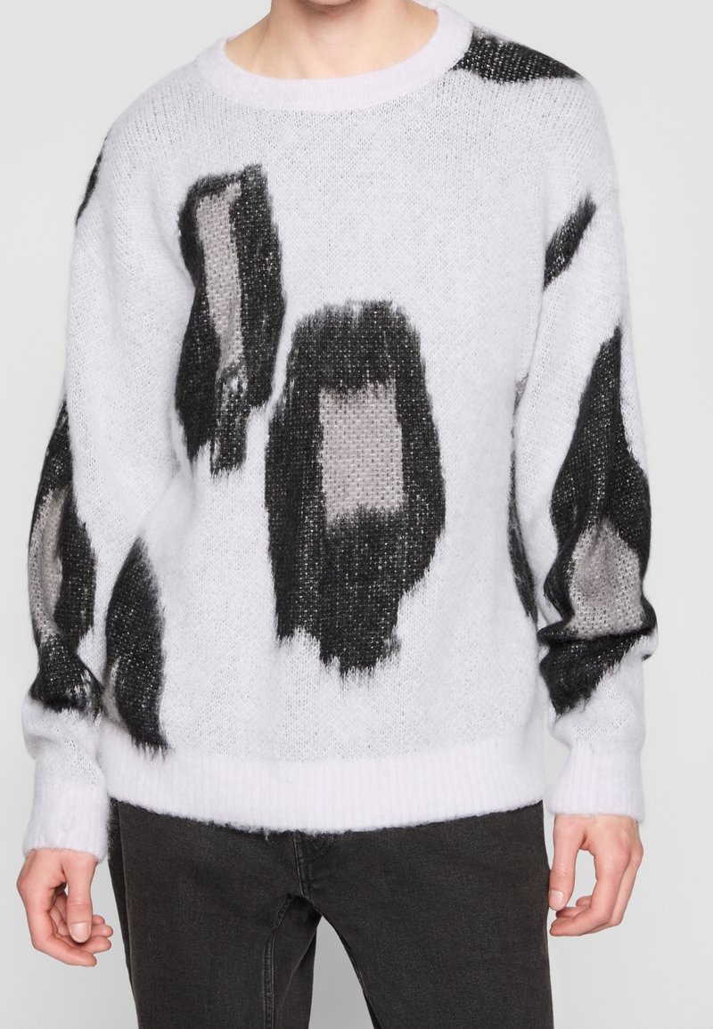 Weißer gestrickter Pullover mit schwarzen und grauen abstrakten Mustern, rundem Halsausschnitt sowie gerippten Bündchen und Saum; weicher, strukturierter Stoff.