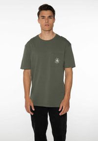 Olijfgroene katoenen t-shirt met een ronde hals, korte mouwen en een links op de borst een zak met een bergafbeelding.