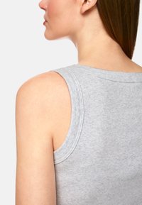 Gray sleeveless top features a ribbed texture, round neckline, and wide armholes, highlighting the shoulder and upper back area.