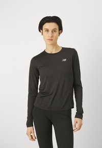 Pitkähihainen musta urheilupaita, jossa on slim fit -malli, pyöreä pääntie ja huomaamaton New Balance -logo, valmistettu hengittävästä, tekstuurista materiaalista.