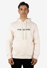 Sudadera con capucha color crema con un bolsillo frontal y un gráfico de texto impreso en negro. Confeccionada con tela suave, de ajuste holgado y capucha ajustable.