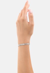 Bracciale in metallo argentato con un motivo texturizzato e intrecciato, aderente al polso, caratterizzato da un design elegante e minimale.