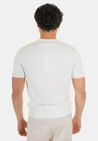 Maglione bianco lavorato a maglia a maniche corte con collo tondo, caratterizzato da una finitura testurizzata e un design aderente. Nessun motivo o dettaglio visibile.
