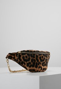 Marsupio con stampa leopardata, tracolla a catena dorata, chiusura con zip, texture morbida di pelliccia e forma arrotondata. Schema di colori marrone e nero.