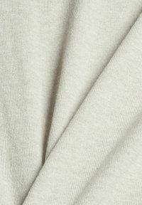 Tissu tricoté gris clair doux plié avec une texture fine visible et un détail en gros plan.