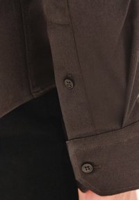 Brązowa koszula o gładkiej teksturze, z zapięciem na guziki i dwoma guzikami na mankietach. Prosty design i dopasowany krój.