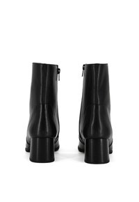 Stivali neri in pelle fino alla caviglia con finitura liscia, tacco a blocco di altezza media e cerniere laterali per una facile vestibilità, caratterizzati da un design elegante e minimalista.