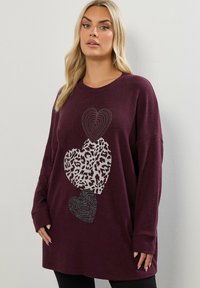 Överdimensionerad burgundy sweatshirt med tre dekorativa hjärtan: ett i silverpaljetter, ett i leopardmönster, ett i zebramönster. Mjuk textur.