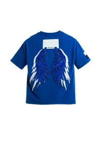 Camiseta de algodón azul con diseños elaborados de alas bordadas en blanco y azul en la parte trasera, con un detalle de etiqueta texturizada encima.