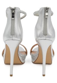 Sandali argentati con tacco alto e finitura lucida, chiusura a zip sul retro e cinturini alla caviglia con decorazioni luccicanti. Design con punta aperta.