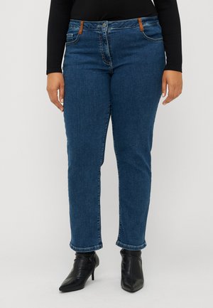 Blå denim jeans med rett snitt, med brune detaljer på midjen, og en litt smalere ben. Brukt med svarte hælboots.