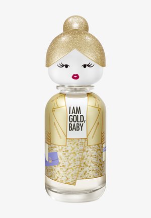 Bouteille en forme de femme avec un chignon de cheveux pailletés dorés, veste et jupe dorées, tenant un sac bleu, étiquetée "I AM GOLD, BABY" sur la poitrine.