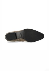 Suela de zapato de vestir de ante marrón con punta afilada y tacón de goma negro, mostrando el nombre de la marca grabado en la suela.