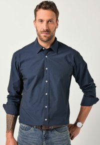 Tmavě modrá kostkovaná košile z látky s límečkem na knoflíky, dlouhými rukávy a bílými knoflíky, spárovaná s džínami z denimu.