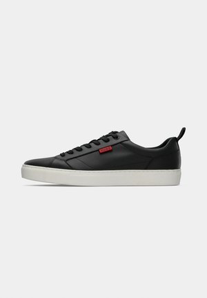 Czarne skórzane sneakersy z białą gumową podeszwą, charakteryzujące się płaskim sznurowaniem i czerwoną metką z logo z boku.