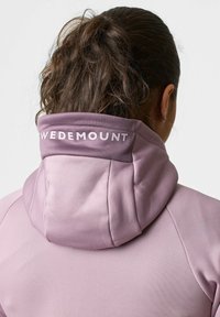 Paarse hoodie met een hoge kraag. De achterkant toont de tekst "SWEDEMOUNT" in het wit. Glad materiaal met een zachte textuur.