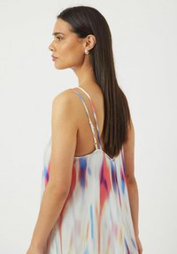 Ärmlös klänning i genomskinligt, lätt tyg med ett färgglatt abstrakt mönster i röd, blå och vit. Justerbara band, flytande design.