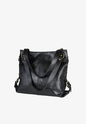 Zwarte leren schoudertas met verstelbare riemen, messing hardware en zichtbare stikdetails, weergegeven tegen een witte achtergrond.