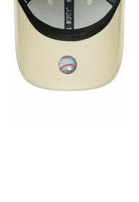 Cappellino da baseball beige con visiera nera, caratterizzato da una toppa circolare che rappresenta una baseball nella parte frontale. Tessuto testurizzato con dettagli di cucitura.