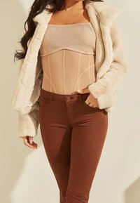 Beżowy body o prążkowanej fakturze, noszone pod kremowym płaszczem z sztucznego futra. Ciemnobrązowe dopasowane jeansy z guzikiem z przodu. Prosty i dopasowany krój.