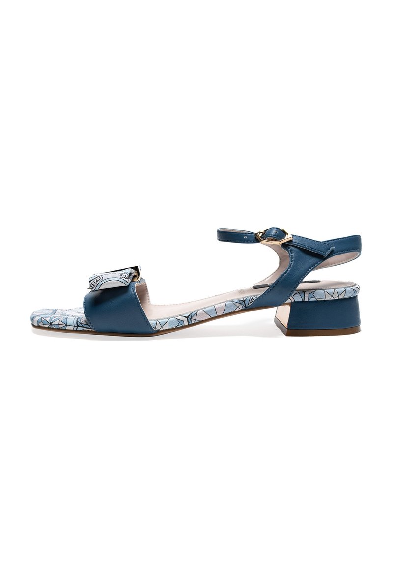 Sandale en cuir bleu avec un petit talon carré, présentant une lanière à motif sur le bout et une lanière de cheville ajustable avec des accents en or.