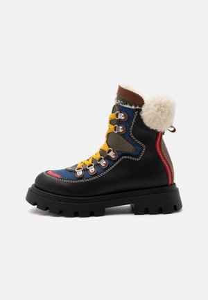 Botte d’hiver noire avec une semelle épaisse, des lacets jaunes, des accents bleus et rouges, des œillets métalliques et une doublure en polaire blanche autour de la cheville.