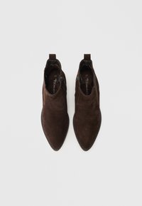 Brūnas zamša potītes zābaki ar smailiem purngaliem, sānu rāvējslēdzējiem un kontrastējošu šuvumu. Aprīkoti ar cilpām ērtai uzvilkšanai. Izmērs 37.