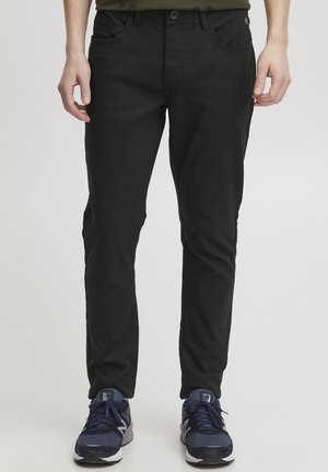 Schwarze Hose im Slim-Fit aus einem weichen, dehnbaren Material. Mit Gürtelschlaufen, Vorderaschen und dezenten seitlichen Akzenten.