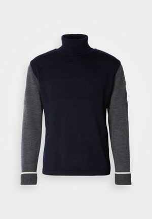 Marineblå og grå strikket genser med høy krage. Har teksturerte mønstre på den øvre delen; kontrasterende grå ermer og ribbede mansjetter.