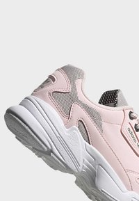 Zapatilla deportiva rosa con malla y cuero sintético, que presenta una parte superior texturizada, un collar acolchado y una suela de goma blanca, diseñada para la comodidad.