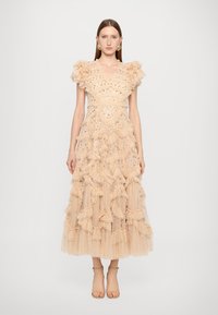 Robe en tulle nude avec des accents froncés, ornée de sequins, corsage ajusté, jupe mi-longue et texture transparente. Chaussures ajustables.