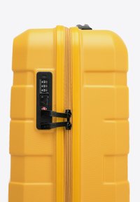 Valigia rigida gialla con finitura texturizzata, doppie zip, lucchetto incorporato e design rettangolare, adatta per i viaggi.